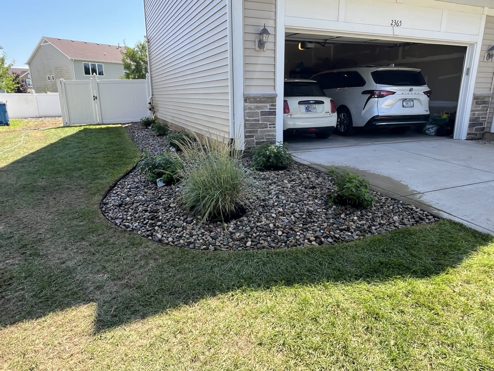 Curved river-rock bed with ornamental grasses installed by Meeks Mowing & Landscaping