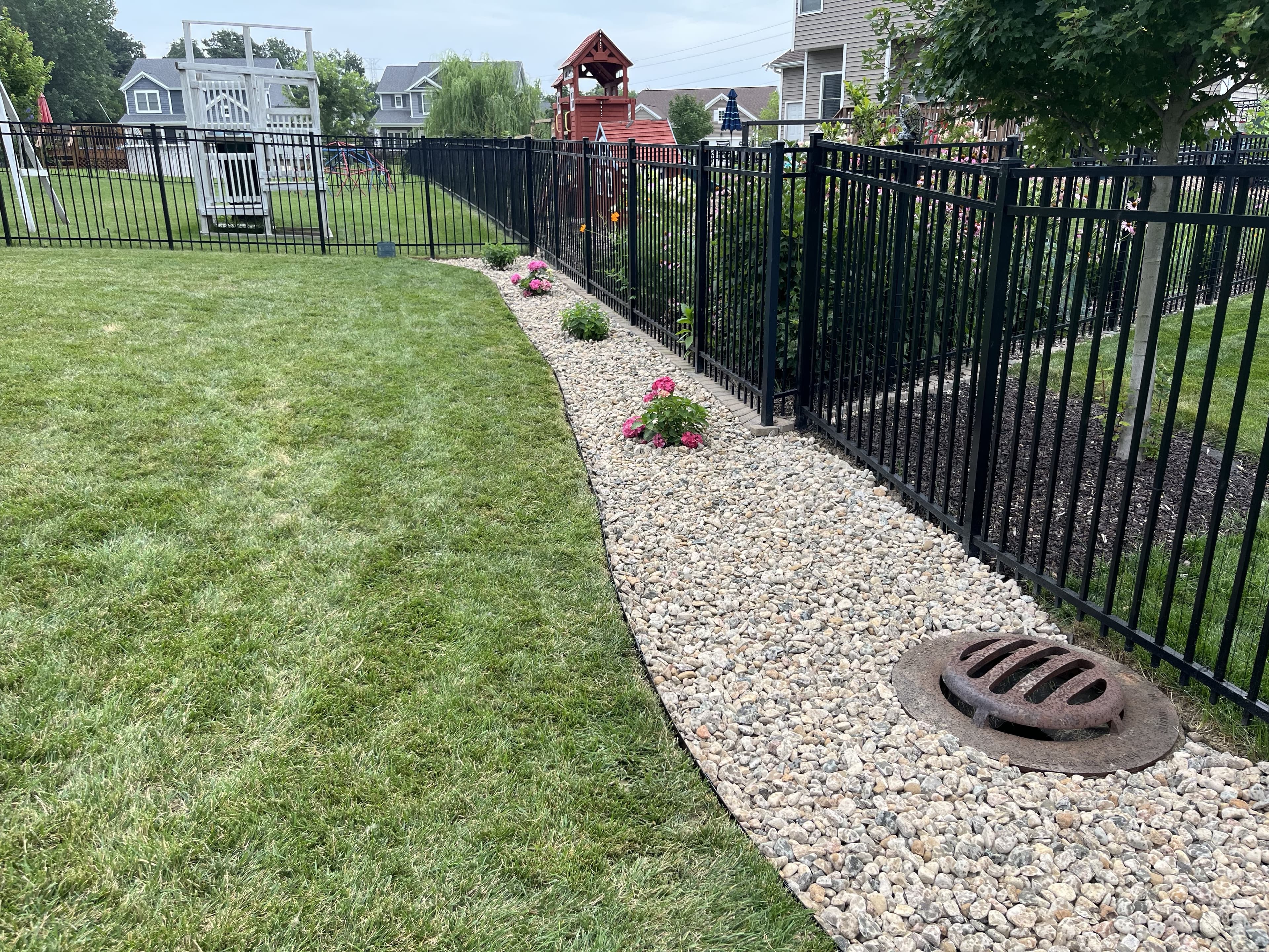 Fence-line river-rock border with hydrangeas