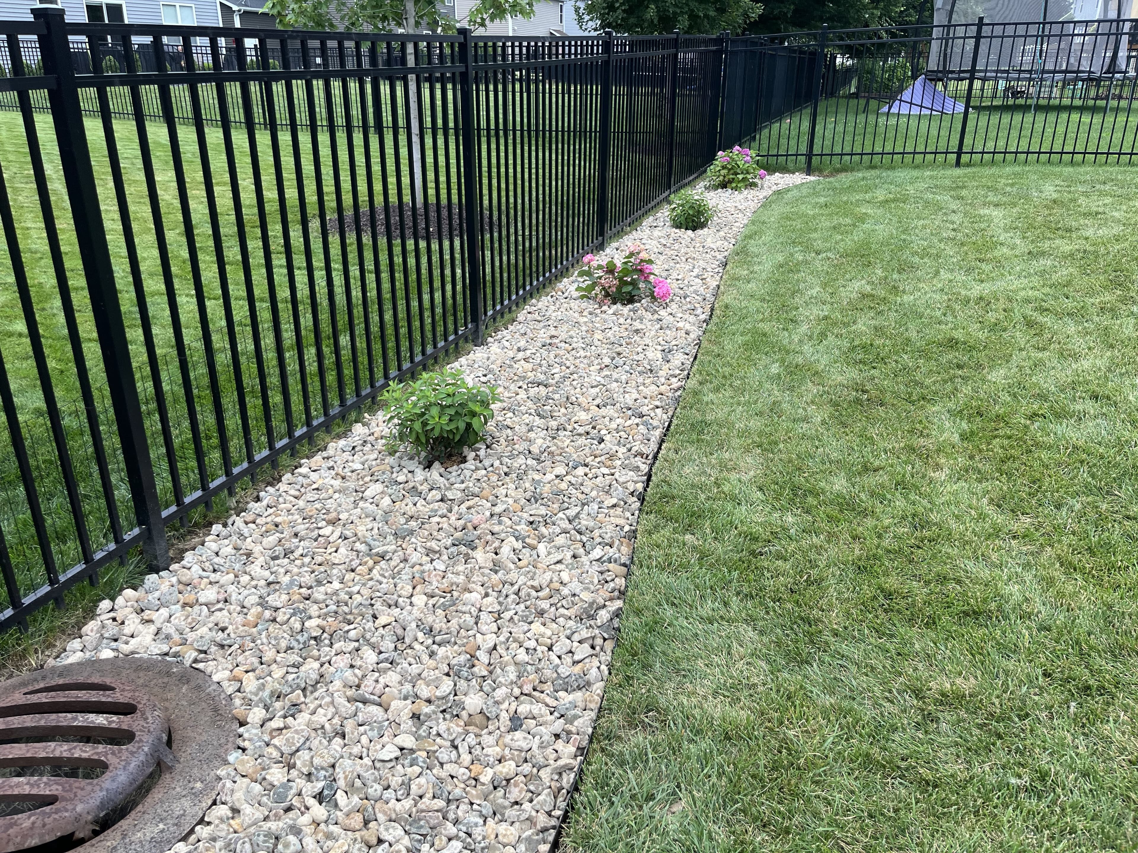 Curved rock border along iron fence